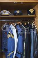 Clothing made for combat. Shot of various military jackets and hats hanging in a closet.