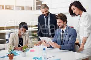 Developing a plan of action. Shot of businesspeople using a digital tablet in an office meeting.