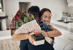 Random acts of kindness. Shot of a young man surprising his wife with flowers at home.