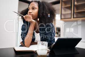 Recess would be awesome right now. Shot of a young girl looking unhappy while doing a school assignment at home.