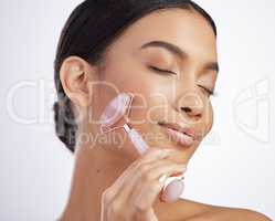 Everyday should feel like a spa day. Studio shot of an attractive young woman using a jade roller on her face against a grey background.