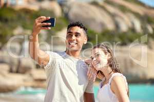 Take a selfie to capture this moment forever. Shot of a young couple taking selfies at the beach.