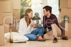 Settling in on moving day. Shot of an affectionate young couple taking a coffee break while moving into a new home.