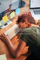 Shes been burning the candle at both ends. Shot of an exhausted young businesswoman sleeping with her head on her desk.