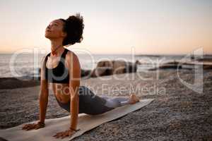 The heavens hold all the answers. Full length shot of an attractive young woman practicing yoga on the beach at sunset.