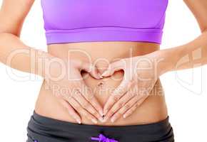 Working out takes a lot of heart. Cropped shot of a woman making a heart-shape on her stomach with her hands isolated on white.