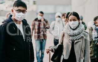 Tourism takes on a new look. Shot of a young man and woman wearing masks while travelling in a foreign city.