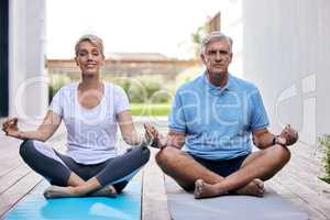 Yoga keeps mind and body sharper. Shot of a mature couple meditating together outdoors.