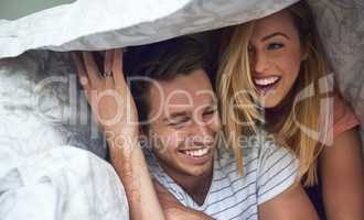 Adventures under the duvet. Shot of a happy young couple having fun under a duvet in bed.