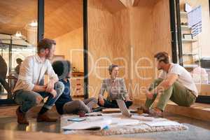 Furthering their lead in the industry through effective teamwork. Shot of a team of designers brainstorming on the floor in an office.