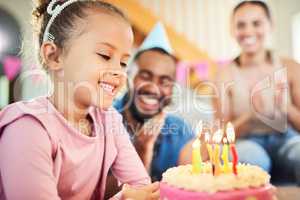 All your wishes can come true. Shot of a little girl celebrating a birthday with her parents at home.