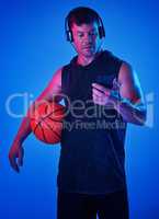 Some music is just what I need to keep me focused. Blue filtered shot of a sportsman wearing headphones while holding a basketball.