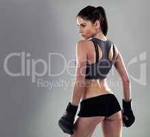 Kickboxing keeps her in shape. Studio shot of a sporty young woman against a gray background.