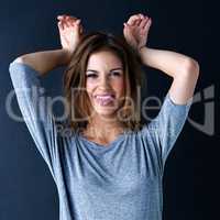 Let your wild side out. Studio portrait of a teenage girl playfully making ears with her hands against a dark background.