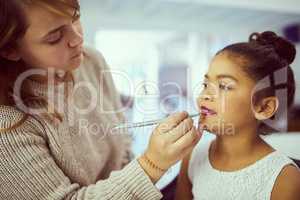 Getting ready to dazzle the crowd. Shot of a stylist applying makeup to a cute little girl in a dressing room.