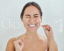 Keeping up with my dental hygiene. Shot of a young woman flossing her teeth in a bathrroom at home.