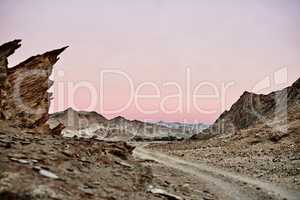 Through an otherworldly landscape. Shot of a dirt road running through rugged terrain.