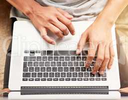 Technology with infinite uses. High angle shot of an unidentifiable man using his laptop at home.