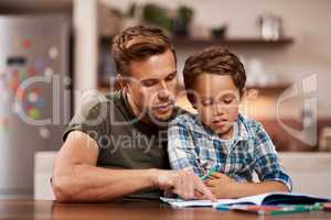 Parents are a childs first and most important teachers. Shot of a man sitting with his son while he does his homework.