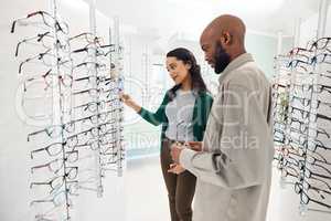 See any that catch your eye. Shot of a an optometrist helping a young man choose a new pair of glasses.