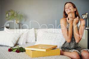 She was blown away on valentines day. Shot of a young woman opening a surprise gift at home.