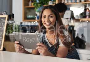Technology is an integral part of how restaurants operate. Portrait of a young woman using a digital tablet while working in a cafe.