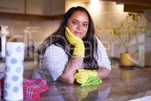 Shes a cleaning whizz. Portrait of a smiling woman leaning on a countertop in a kitchen.