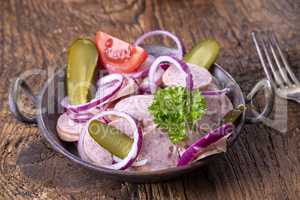 Bayerischer Wurstsalat auf dunklem Holz