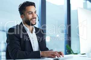 Please give me a moment and I will help you. Shot of a young businessman working in a call center.