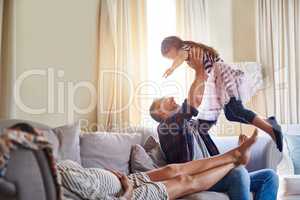 Domestic bliss at its best. Shot of a father playing with his daughter while her pregnant mother relaxes with them on the sofa.