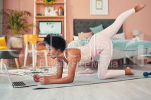 Perfecting her form with some helpful online tutorials. Shot of a young woman using a laptop while exercising at home.