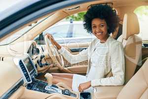 Kicking things into gear. Portrait of a cheerful young businesswoman seated in the driver seat of a car on her way to work during the day.