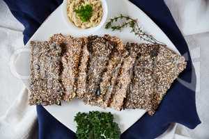 Good food, good life. Overhead shot of seed crackers on a white serving plate.