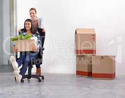 Wheeling her into the new office. Shot of two female entrepreneurs moving into a new office.