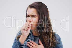 Shes gonna need to go to the doc. Studio shot of an attractive young woman coughing against a grey background.