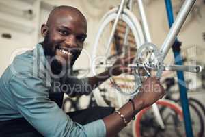 Dont worry Its such a tiny problem to fix. Shot of a handsome young man crouching in his shop and repairing a bicycle wheel.