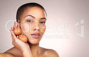 Eggs can provide hydration and elasticity to the skin. Studio shot of a beautiful young woman holding eggs against her face.