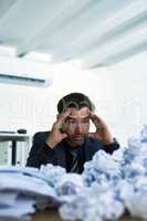 Im never going to get through all of this. Shot of a stressed out businessman sitting at his desk overwhelmed by paperwork.