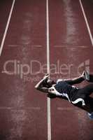 Life in the fast lane is tiring. A young runner lying down on the tartan track.