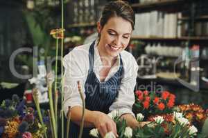 Everyone loves flowers. Cropped shot of an attractive young florist arranging flowers inside her plant nursery.