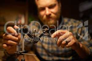 Using his expertise to create the ultimate lure. Shot of a man making fishing lures in his workshop.