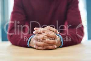 Patience breeds success. Shot of an unidentifiable businessman sitting with his hands folded in the office.