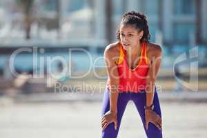 Running is simple but it aint easy. Shot of a sporty young woman taking a break after an intense workout.