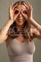 Like what you see. Studio portrait of an attractive young woman making a face against a brown background.