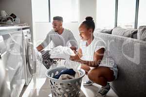 Division of labour isnt just for the workplace. Shot of a happy young couple doing laundry together at home.