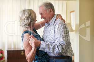 Staying in love is a special thing indeed. Shot of a happy senior couple dancing together at home.