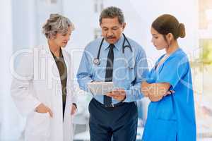 Going over some medical records. Shot of three healthcare professionals looking over medical records on a tablet.