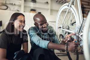 I fixed that. Shot of two young business owners crouching in their shop and fixing a bicycle wheel.
