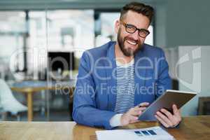 I craft all my winning concepts on this handy device. Portrait of a young businessman working on a digital tablet in an office.