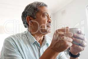 Thoughts over coffee. Shot of a senior man drinking coffee at home.